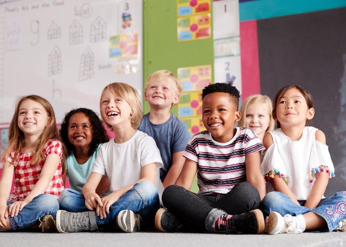 Group Of Elementary School Pupils Sitting On Floor In Classroom