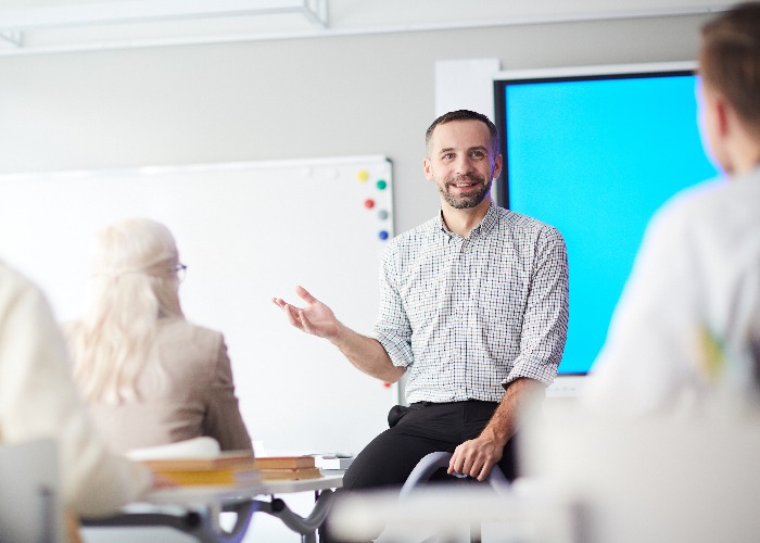 Happy confident teacher explaining his students what he thinks about new subject