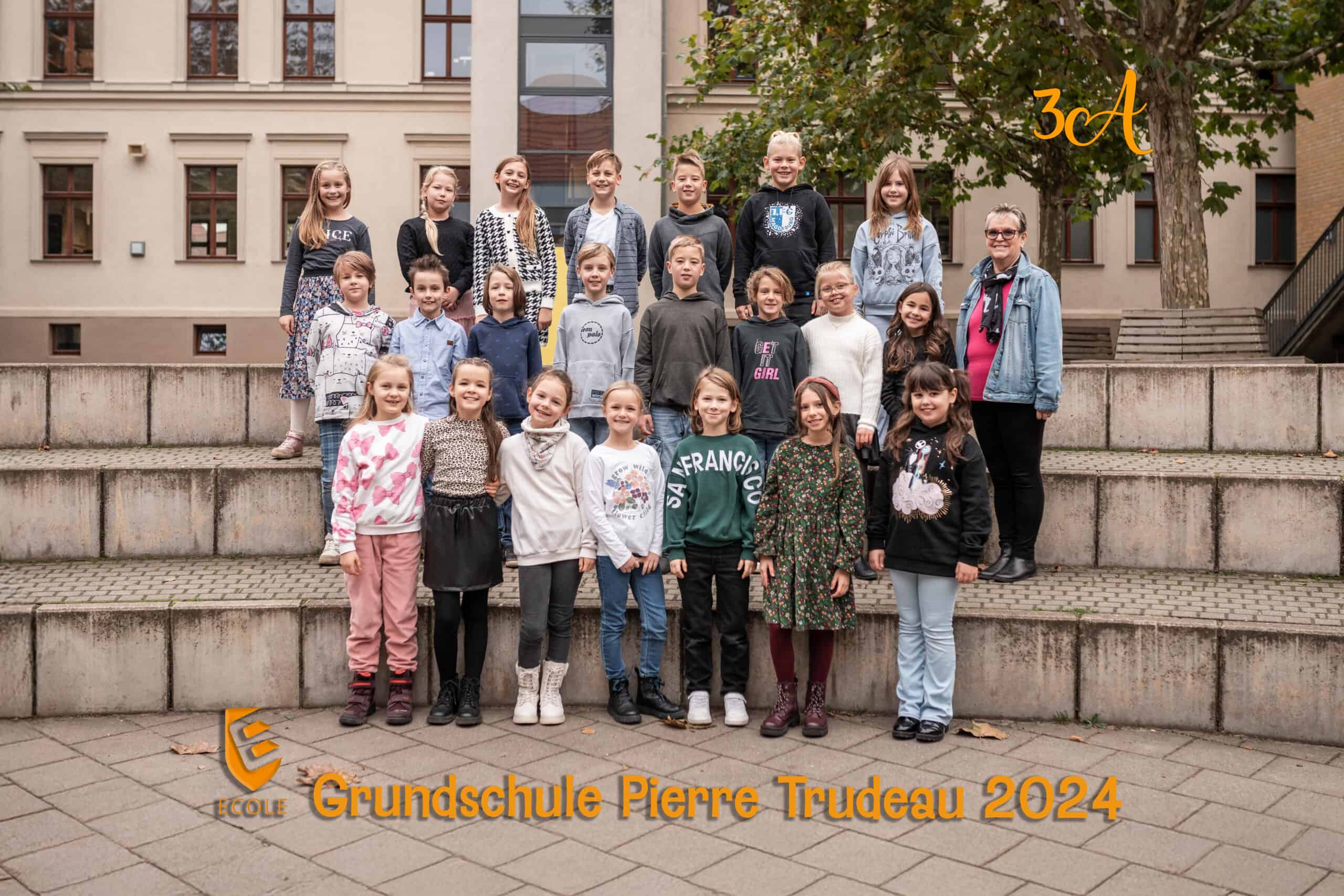 Schulklasse 3a mit Lehrerin lächeln auf Treppe; Herbstfarben, Baum im Hintergrund.