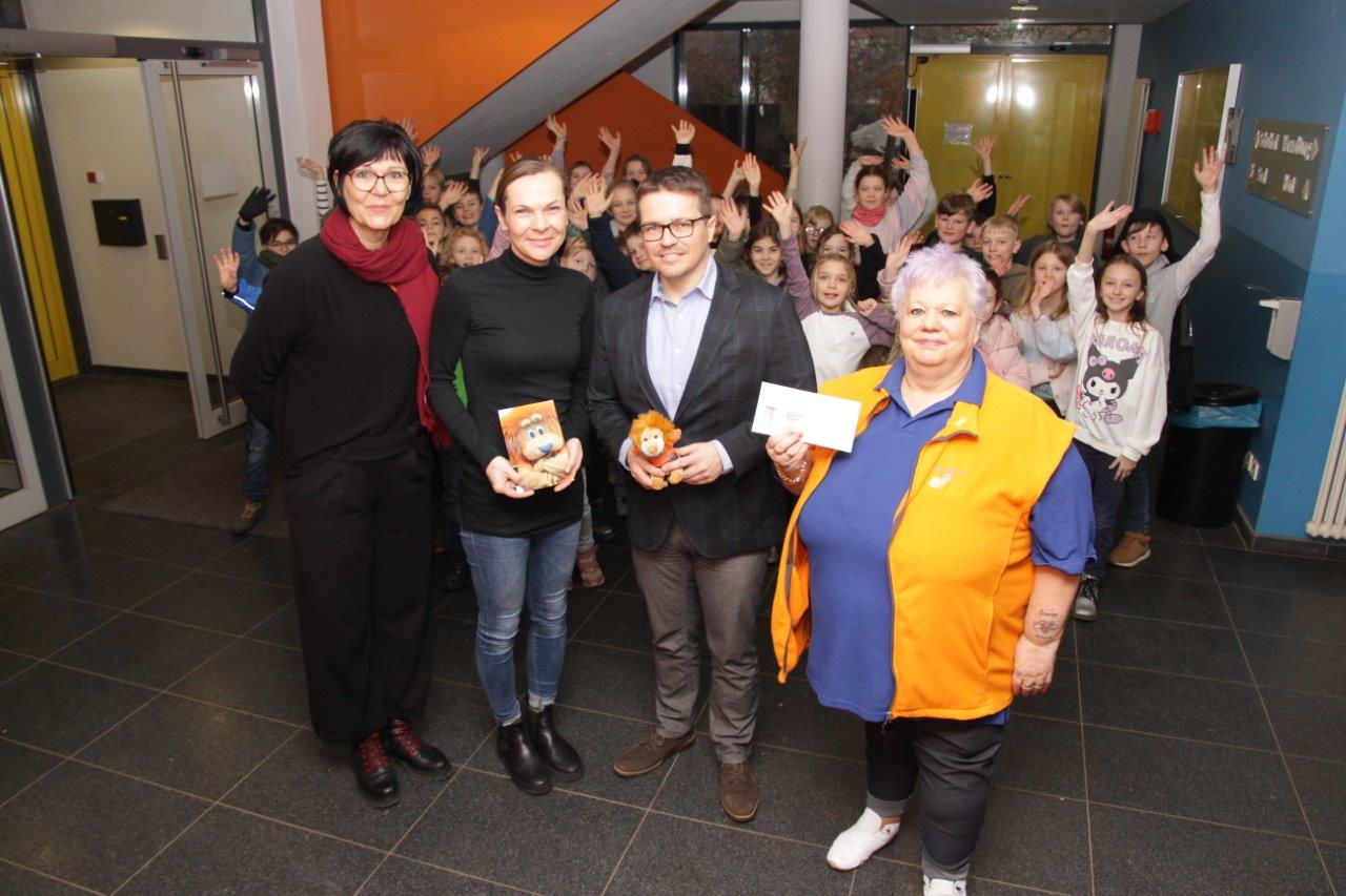 Vier Erwachsene mit Geschenken, umgeben von Kindern; lächelnd in bunter Umgebung.