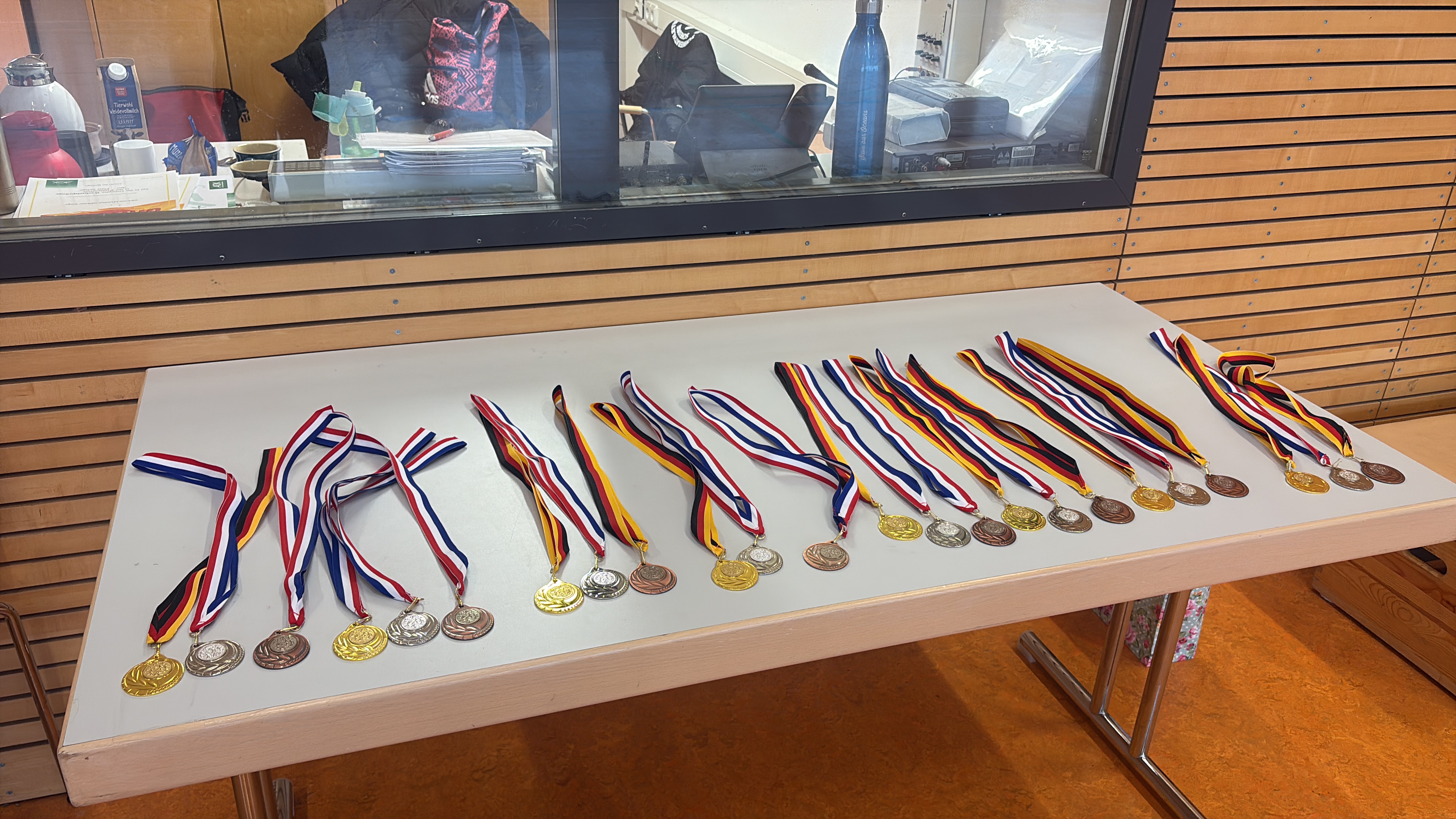 Medaille-Sammlung auf Tisch; verschiedene Farben; glänzend; sortiert in Reihen; silberne, goldene Medaillen.