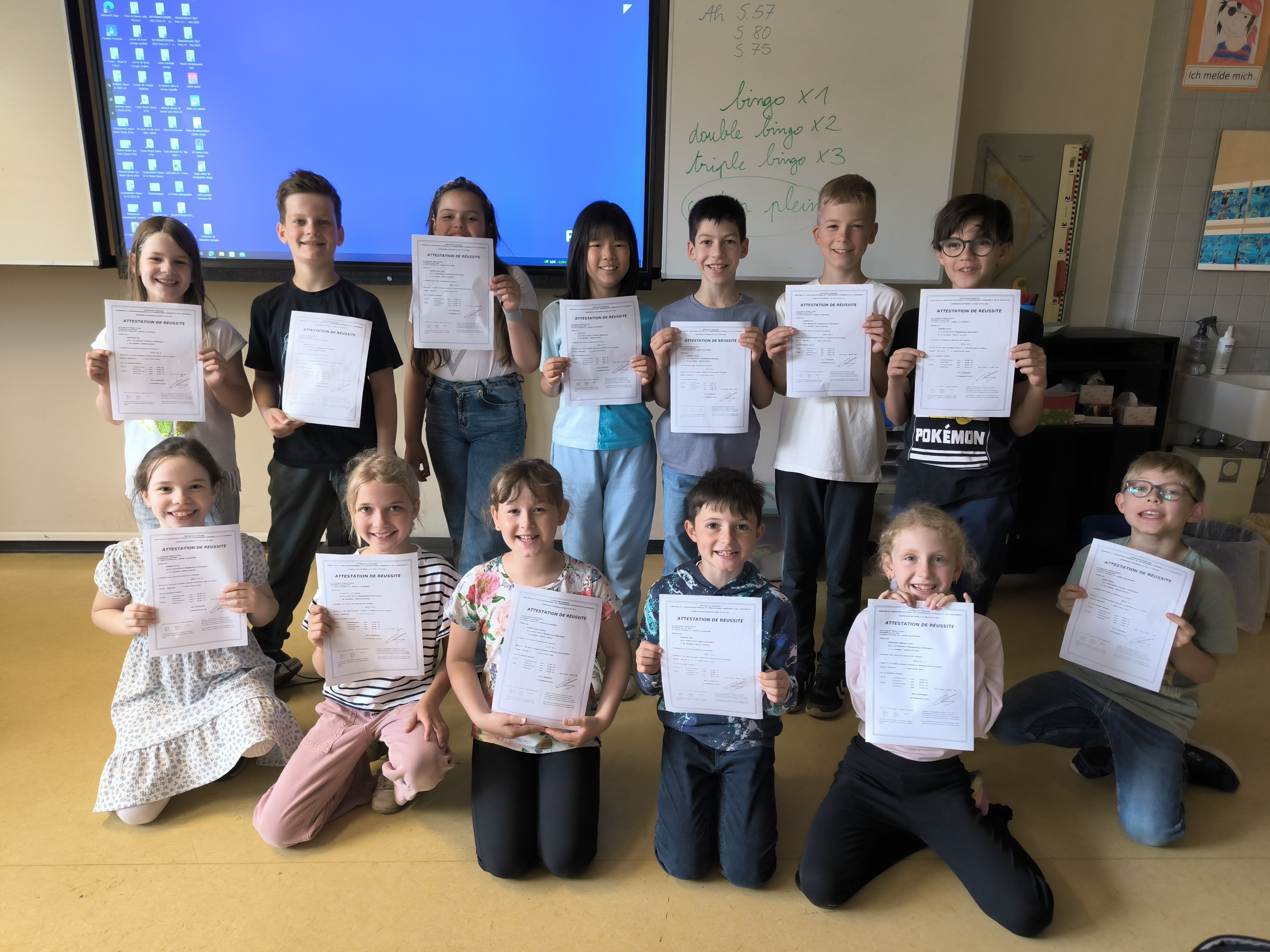 Gruppe von Kindern lächelt und hält Zeugnisse, bunte Kleidung, Klassenzimmerhintergrund.