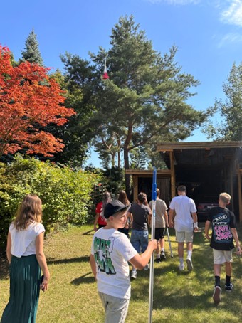 Eine Gruppe von Kindern mit sommerlicher Kleidung spielt im sonnigen Garten.