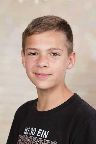 Junger Mann mit freundlichem Ausdruck, hellbraunes Haar, schwarzes T-Shirt.