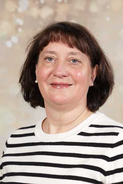 Eine lächelnde Frau mit halbhohen braunen Haaren trägt ein gestreiftes Oberteil.