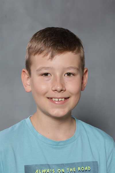 Junger Junge lächelt freundlich, trägt ein blaues T-Shirt.