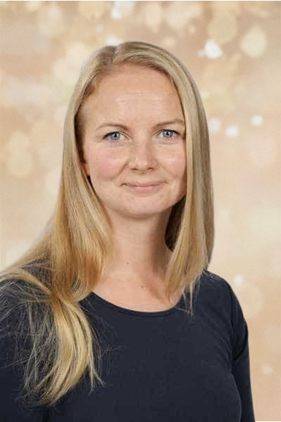 Eine lächelnde Frau mit langen blonden Haaren vor hellem Hintergrund.