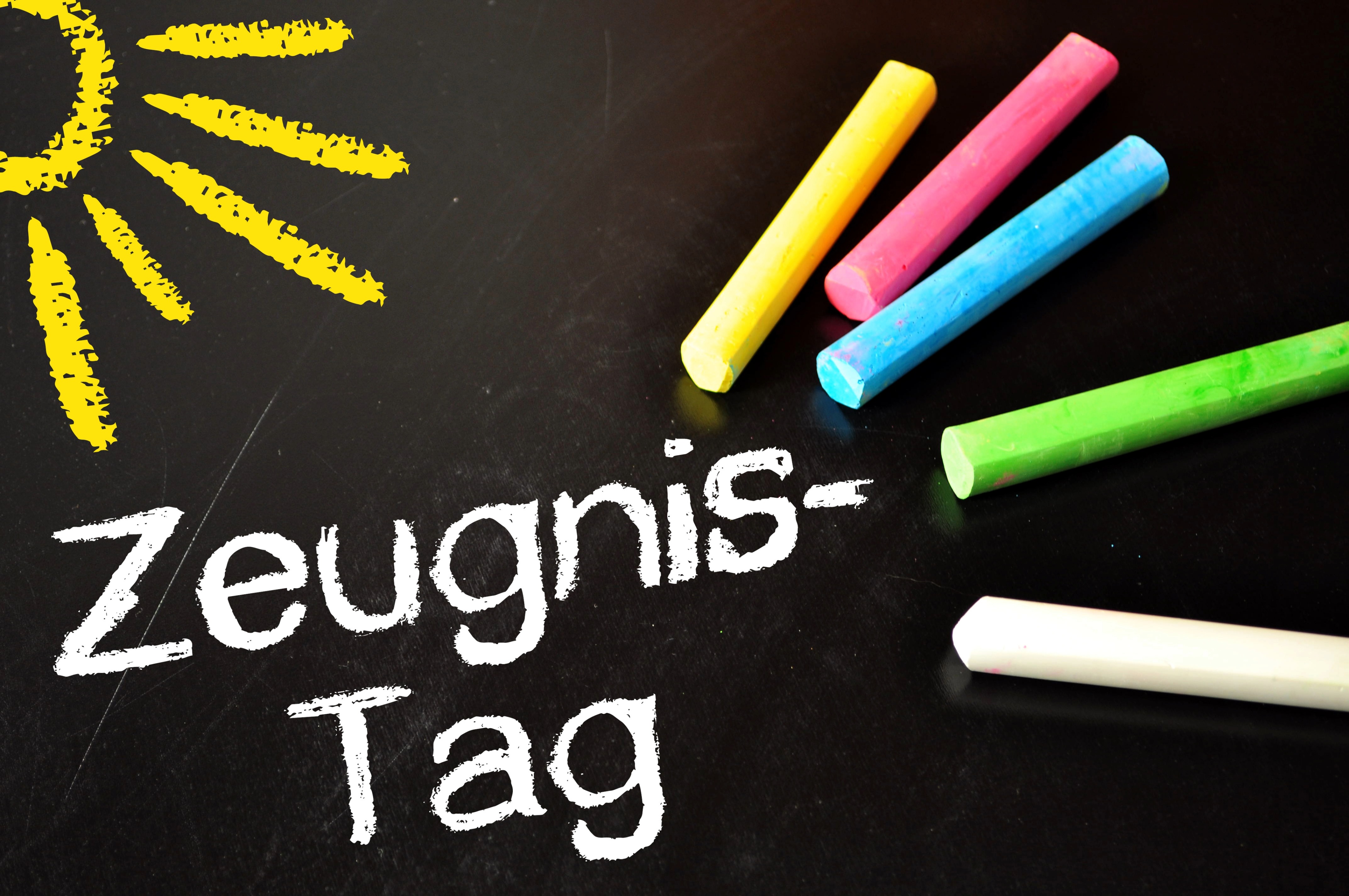 Bunte Kreide auf einer Tafel mit der Aufschrift "Zeugnis-Tag" und gemalter Sonne