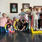 Eine Gruppe von fröhlichen Kindern hält bunte Buchstaben, die "EDEBE" bilden