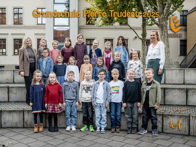 Eine Gruppe von 23 Grundschulkindern und zwei Lehrerinnen posieren freundlich draußen