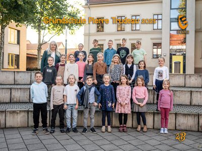 Eine Gruppe fröhlicher Schulkinder steht draußen auf Steinstufen in bunter Kleidung