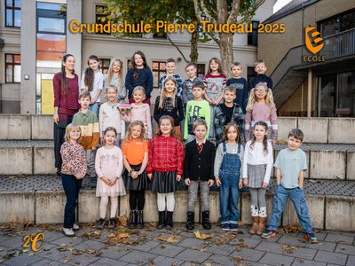 Eine fröhliche Gruppe von Grundschulkindern posiert in bunter Kleidung draußen