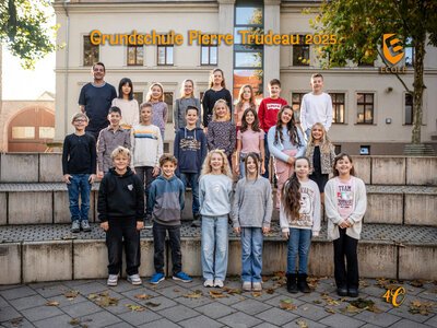 Eine fröhliche Gruppe von Grundschülern posiert im Freien vor der Schule