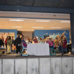 Eine Gruppe von Kindern steht fröhlich in einem hell erleuchteten Klassenraum mit blauer Wand