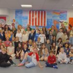 Lachende Gruppe im Raum vor USA Flagge, bunte Wandbilder und Banner