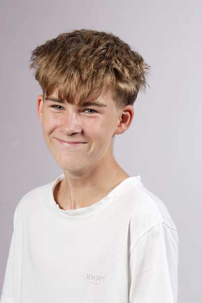 Ein laechelnder junger Mann mit blonden Haaren und weissem Shirt