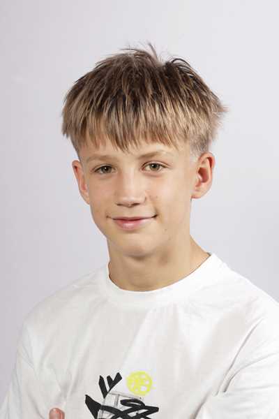 Ein laechelnder blonder Junge im weissen T-Shirt vor hellem Hintergrund