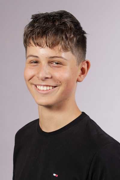 Ein laechelnder junger Mann mit braunen Haaren und schwarzem T-Shirt