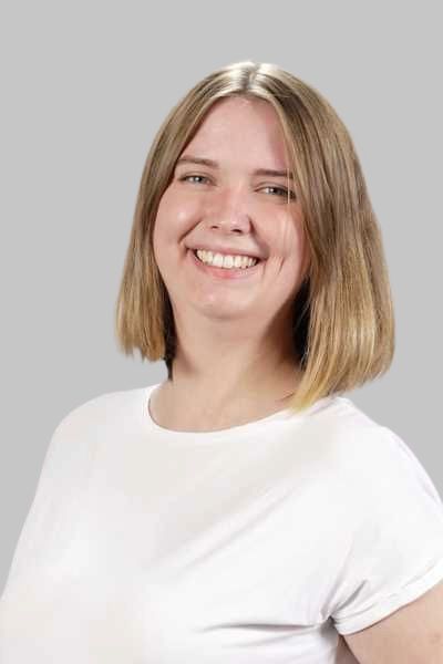 Laechelnde junge Frau mit blondem Bob und weissem Shirt vor grauem Hintergrund