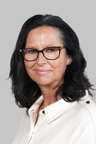 Laechelnde Frau mit dunklem Haar und schwarzer Brille in cremefarbener Bluse
