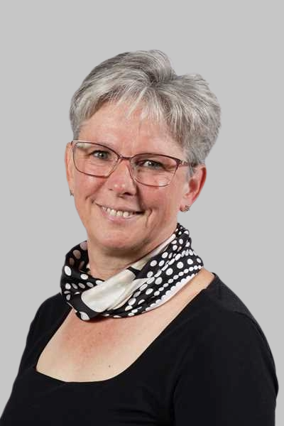 Laechelnde Frau mit grauen Haaren, Brille und schwarz weissem Halstuch