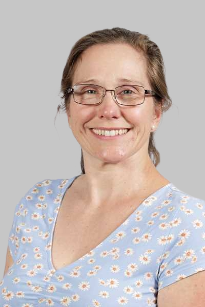 Laechelnde Frau mit Brille traegt ein hellblaues Bluemchenshirt