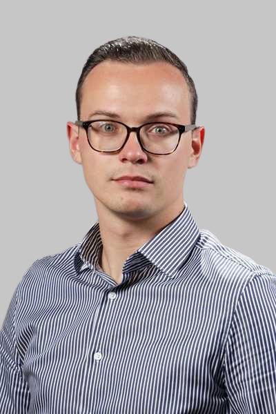 Ein junger Mann mit Brille und gestreiftem Hemd blickt ernst in die Kamera