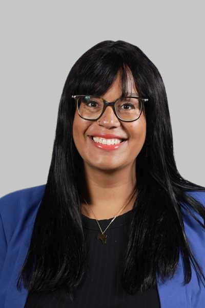Laechelnde Frau mit langen dunklen Haaren Brille und blauem Blazer
