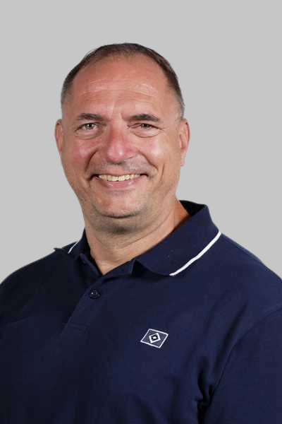 Laechelnder Mann mit kurzen Haaren in dunkelblauem Poloshirt mit Logo