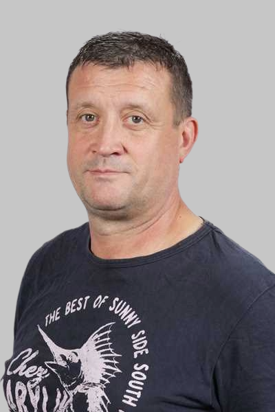 Ein Mann mit kurzen Haaren traegt ein dunkelblaues Shirt mit Fischmotiv