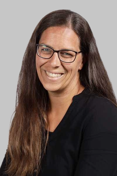 Laechelnde Frau mit langen braunen Haaren Brille und schwarzem Oberteil