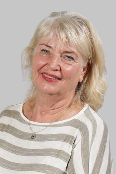 Laechelnde blonde Frau mit gestreiftem Oberteil und blauer Halskette