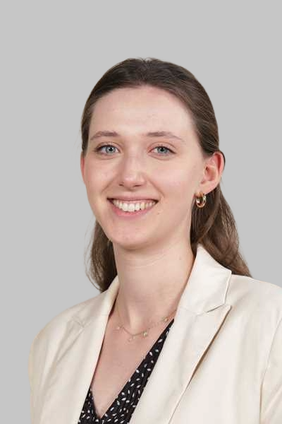Laechelnde junge Frau mit braunen Haaren im cremefarbenen Blazer