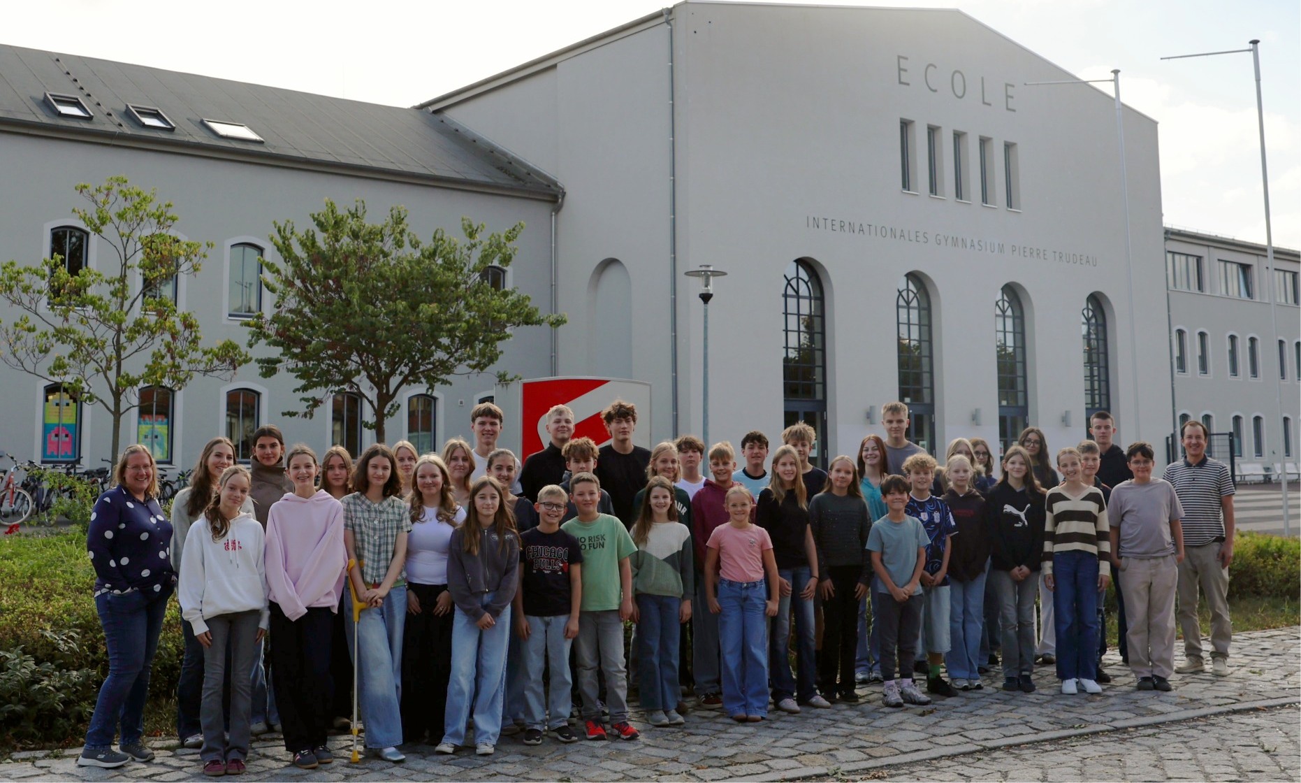 Laechelnde Schuelergruppe vor dem Internationalen Gymnasium Pierre Trudeau