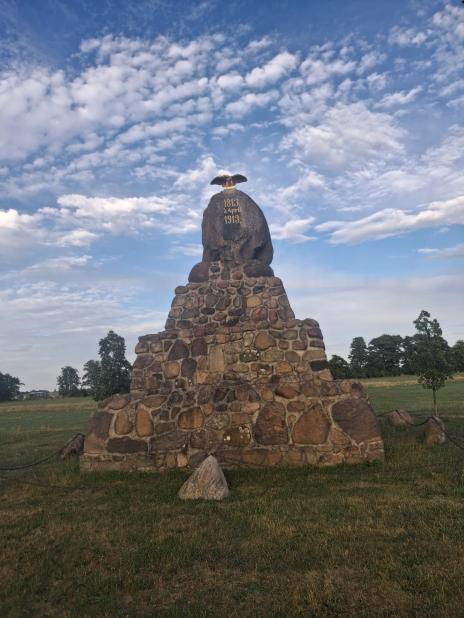 Steinernes Denkmal mit Adlerfigur und Jahreszahlen unter blauem Himmel